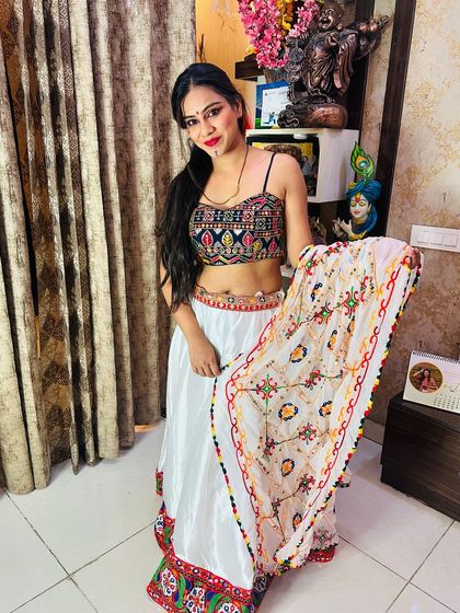 A model posing with the white satin lehenga, showcasing the detailed dupatta and the vibrant colors of the blouse.