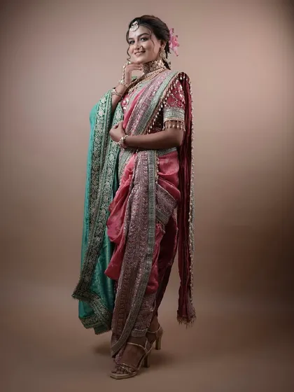 A full-length shot of a stunning Marathi bridal look, featuring a unique pink and teal Nauvari saree. We also teach saree draping in our course.