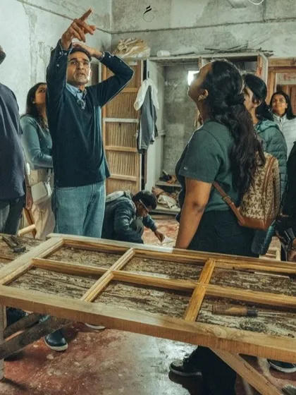 A hands-on demonstration during a Restoration Clinic workshop. An expert shows students how to assess and repair a traditional wooden door frame, bridging the gap between theory and practical craft.