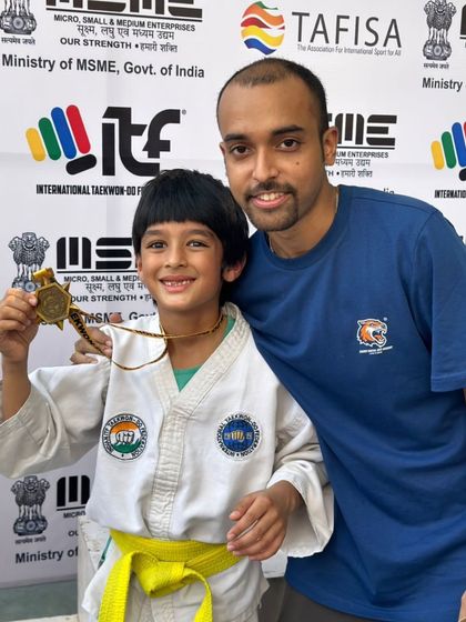 A young student and his coach share a happy moment after a gold medal win.