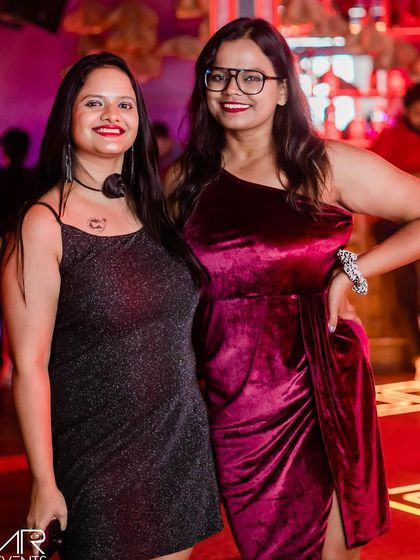 Two friends in glamorous outfits, ready for a night of dancing.