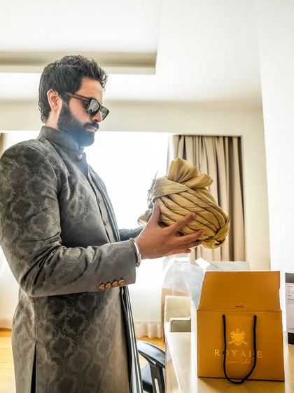 A quiet moment of preparation for the groom. Holding his safa (turban), he gets ready for the most important day, a candid shot filled with anticipation.