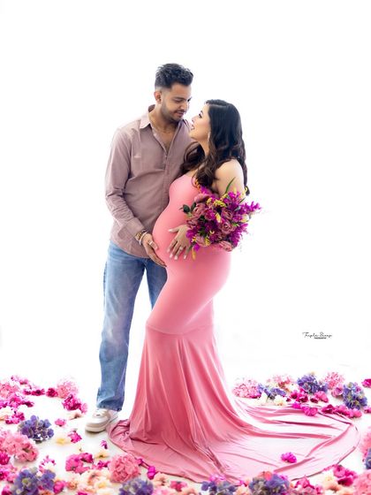 Using props like fresh flowers can add a touch of color and softness to your maternity photos. Here, the mom-to-be looks radiant in a pink gown.