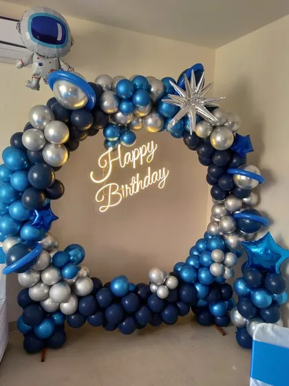 A cool outer space theme for a birthday party. This circular balloon arch in shades of blue and silver is decorated with planet and astronaut foil balloons.