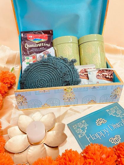 This elegant blue printed trunk box is a gift in itself. Inside, it holds ceramic jars of goodies, coasters, and delicious wafers, making for a beautiful and useful Diwali present.