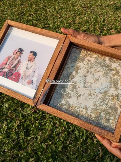 A close-up of the 8x8 inch folding teak wood frame, showing the custom initial design on the resin side and a beautiful wedding photo on the other.