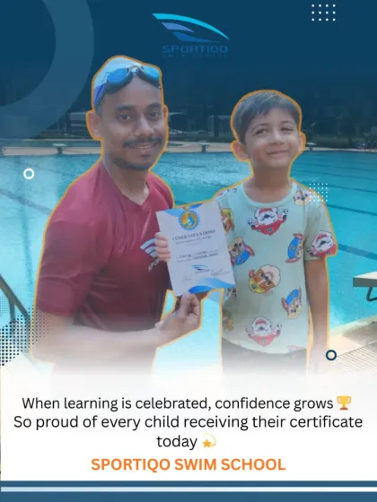 A young swimmer proudly receives his certificate from his coach. Celebrating these milestones is key to building a child's belief in themselves.