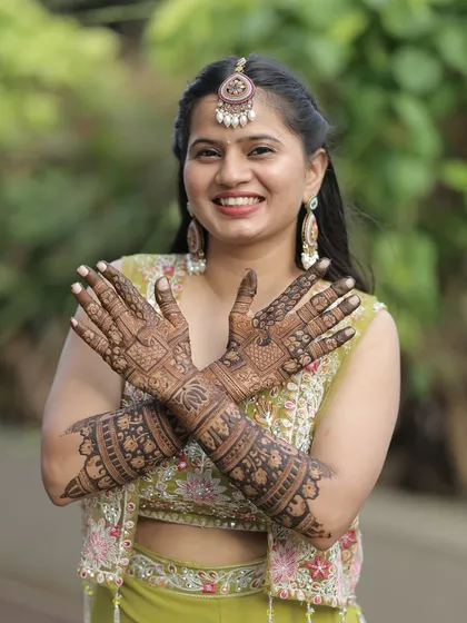 A happy bride posing with her full bridal mehendi. The design is a beautiful mix of traditional patterns and her smile is the perfect accessory.