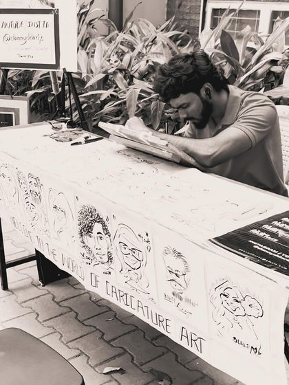 An action shot of me working at my table, which is covered in examples of my caricature art.