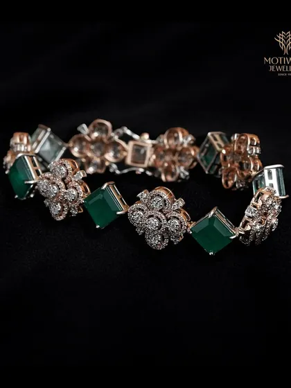 A luxurious bracelet with alternating links of emerald-cut green gemstones and floral diamond clusters.