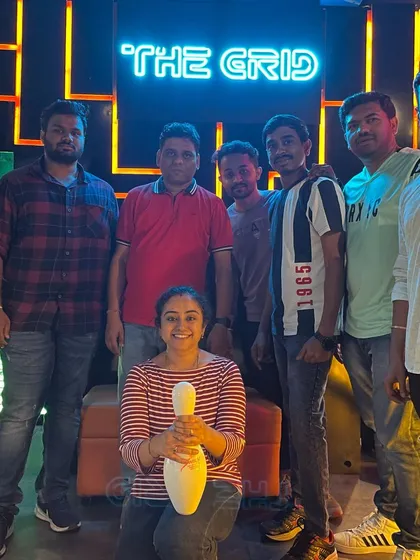 A group posing with a bowling pin in front of our logo.