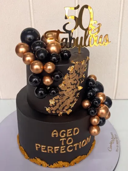 Celebrating a milestone like 50 calls for something truly fabulous. This two-tiered cake features a bold, black fondant finish, accented with cascading edible gold leaf, and a garland of black and gold spheres for a modern, luxurious feel.