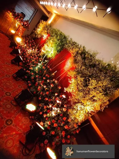 For a touch of luxury, nothing beats a dense wall of fresh flowers. This pathway is lined with thousands of red roses and baby's breath, lit by spotlights to create a rich, romantic atmosphere for a wedding or an elegant party.