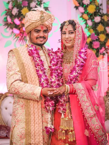 A happy, classic portrait of the newly married couple. Their bright smiles and coordinated outfits against the floral backdrop perfectly capture the joy of the wedding day.