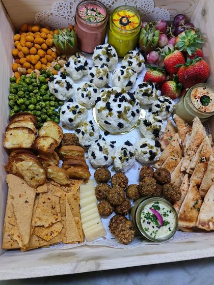 A large grazing box filled with a variety of cheeses, dips, crackers, fresh fruits, and falafel. A complete party spread delivered to your door.