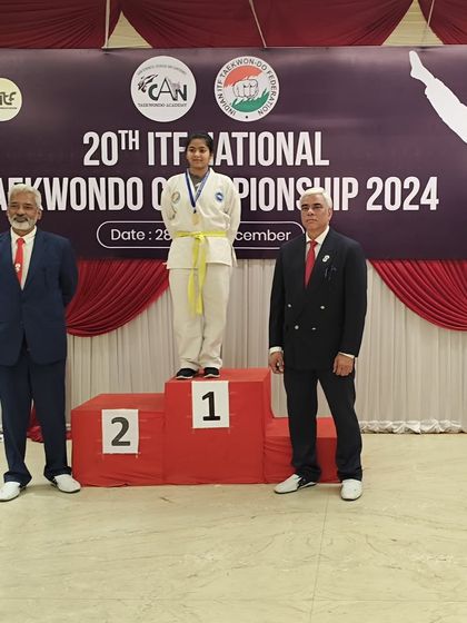 A yellow-belt student takes her place on the podium, showcasing the success of our athletes across all belt levels.