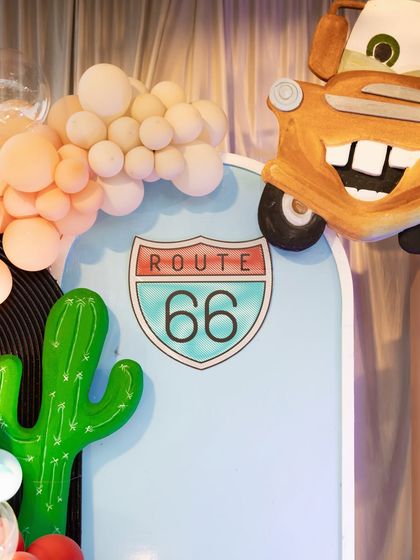 A close-up of the Route 66 sign and a Mater cutout, iconic elements from the Disney Cars universe.