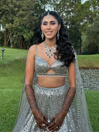 The full sangeet look in an outdoor setting. The makeup is fresh and vibrant, matching the energy of the event.