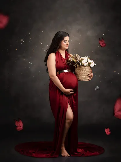 A classic portrait in a satin red gown against a dark backdrop. The client holds a basket of flowers, creating a timeless and elegant image with a touch of romance.