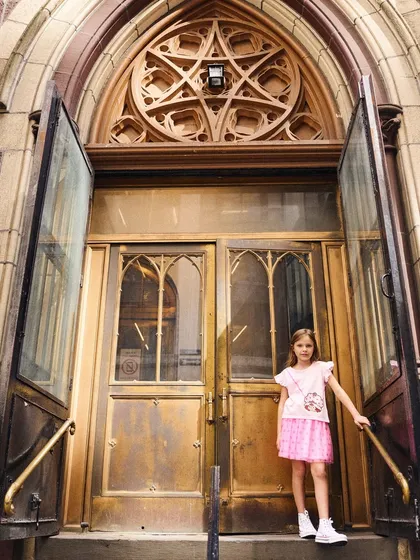 Using the grand architecture of a New York doorway as a backdrop. The contrast between the small subject and the large, ornate doors creates a visually interesting composition for this kids' fashion campaign.