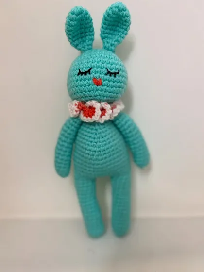 A sweet and sleepy 10-inch bunny, this amigurumi toy is made in a lovely teal color with a cute ruffled collar. It's perfect for cuddling.