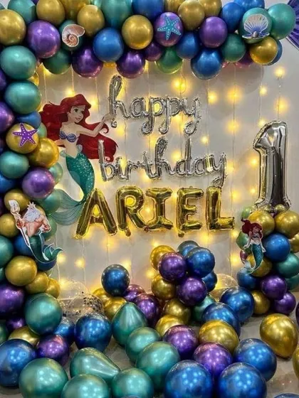 For a little girl's first birthday, I did this magical Little Mermaid theme. The balloon garland uses purple, teal, and gold balloons with seashell details. I also added Ariel character cutouts and fairy lights behind the 'Happy Birthday' foil balloons to make it sparkle.