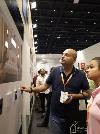 A visitor couple examines a wall of smart switches, discussing the aesthetic and functional options for their project. The expo caters to both professionals and discerning end-users.