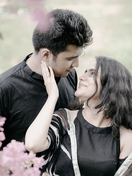 A close-up shot capturing the loving gaze between a couple, framed by delicate pink flowers.