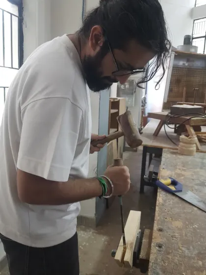 We believe in the power of hand tools. A student carefully uses a chisel and mallet to create a precise joint, a fundamental skill that teaches control and attention to detail.