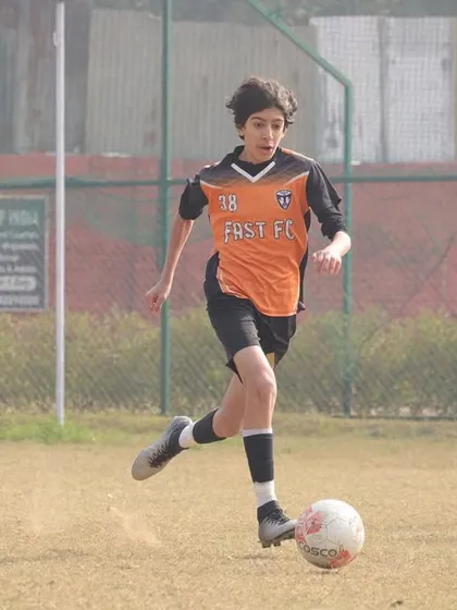 A young player driving forward with the ball at his feet during the Gurgaon Winter Cup.