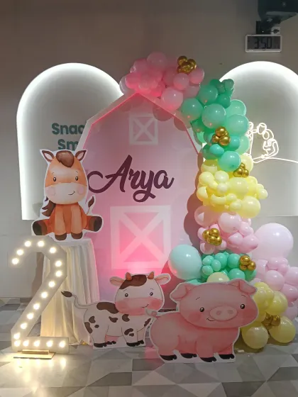 A sweet farm animal theme for Arya's 2nd birthday. The centerpiece is a barn-shaped backdrop, surrounded by cute farm animal cutouts, a marquee number '2', and a pastel balloon garland.