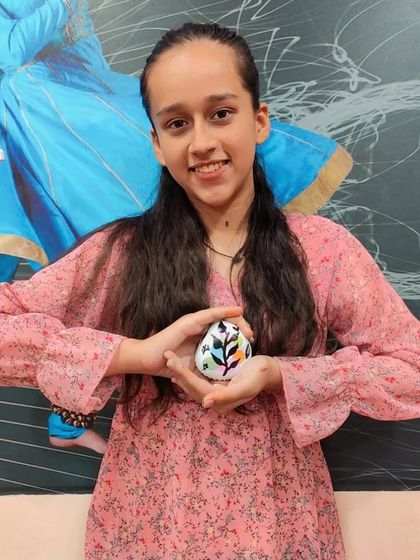 Even a simple stone can become a canvas. This student shows off her beautifully painted pebble, a great example of finding art in nature.