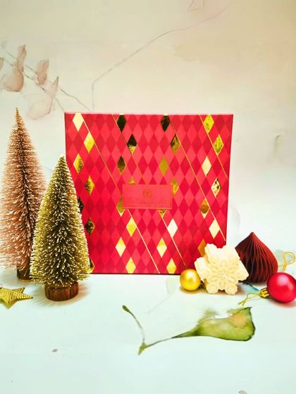 The elegant red and gold patterned box for my Christmas collection, styled with miniature Christmas trees and ornaments to set a festive mood.