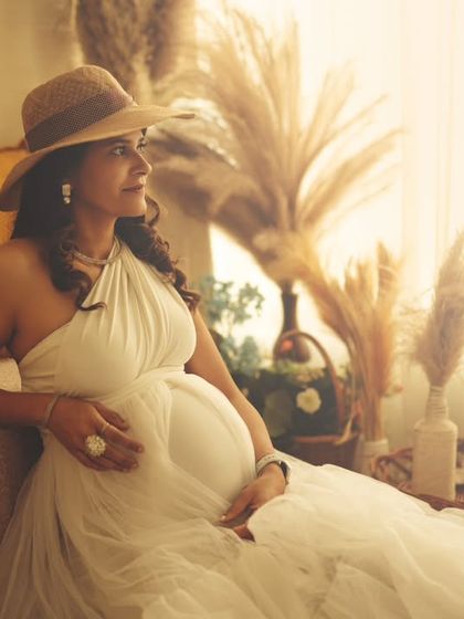 A warm, sun-kissed portrait of an expecting mother in a stylish hat, creating a relaxed and chic vibe.