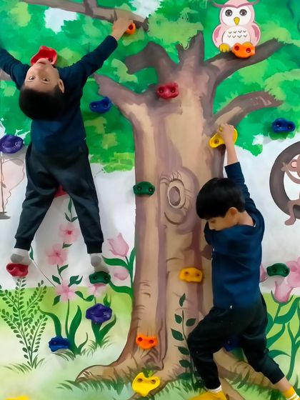 There's always a new way to climb. This angle shows the kids using different holds and techniques to challenge themselves on our indoor climbing wall, a highlight of our kids gym.