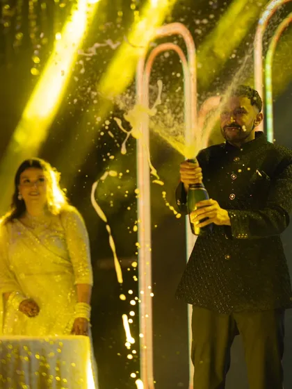 A moment of pure celebration as the groom pops a bottle of champagne at the reception. This shot captures the high energy and excitement of the evening party, a key part of the wedding story.