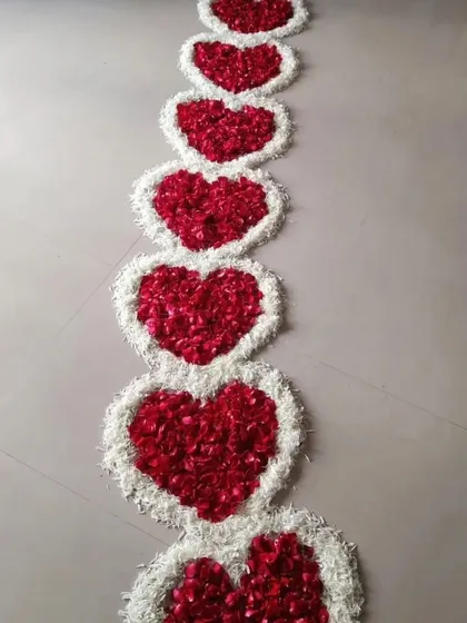 A close-up view of the pathway made from red and white flower petals, arranged in a series of hearts. This is a beautiful and symbolic way to decorate the floor for a baby's first steps into the home.