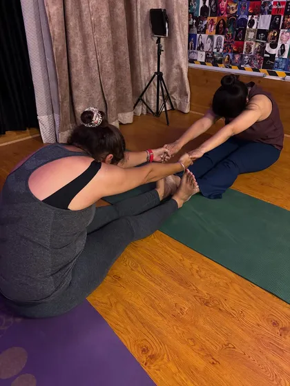 A perfect day for us includes dim lights, a good stretch, and seeing our members progress. Here I am assisting a student with a partner stretch.