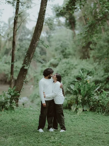 The couple embracing in a lush green forest, a moment of quiet intimacy in nature.