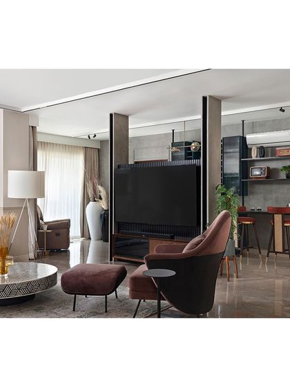 A sleek TV unit with a textured finish acts as a minimal partition between the living area and the bar. This creates a sense of separation without closing off the space, maintaining an open and social feel.