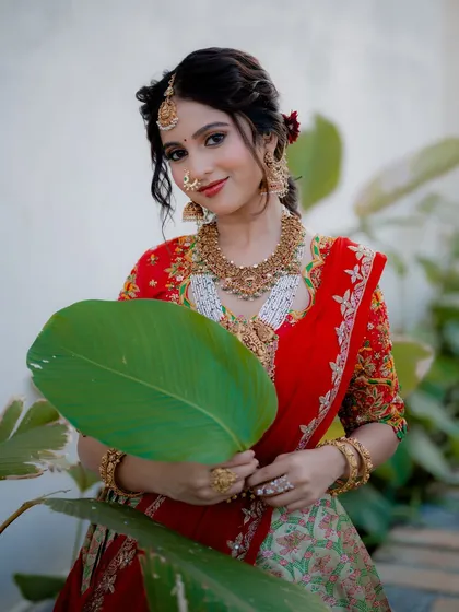 A beautiful portrait of actress Niveditha Gowda holding a large leaf. This creative composition adds a natural and unique element to the traditional photoshoot.
