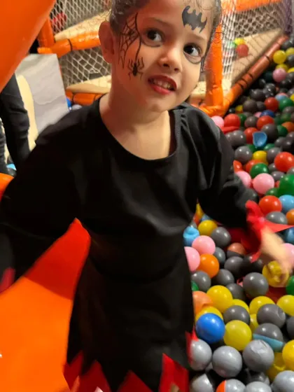 A girl with spooky bat face paint, ready to enjoy the Halloween festivities in the ball pit.