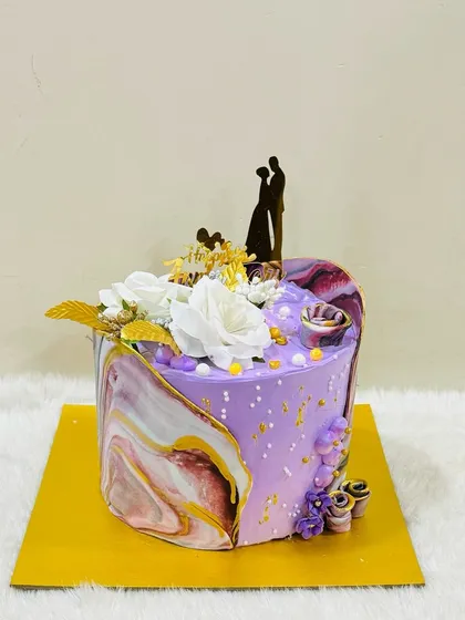 A unique heart-shaped cake with a stunning purple and gold marble effect. The silhouette topper of a couple makes it a perfect, artistic choice for an anniversary.