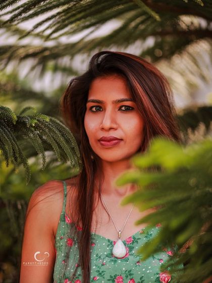 Peeking through lush green leaves, this portrait feels intimate and connected to nature. Her direct gaze is captivating, drawing the viewer in.