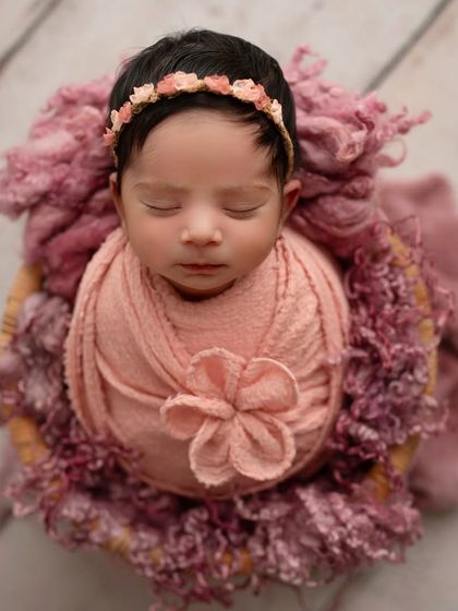 An overhead shot of this little button, all wrapped up in pink and nestled in a basket. This pose is perfect for showing off their round, squishy cheeks.