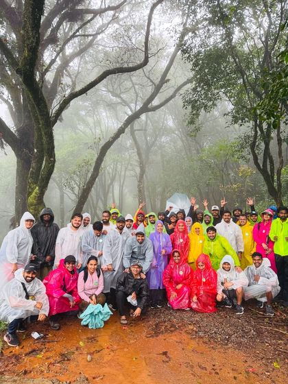 A large, energetic group in colorful raincoats on the muddy Bandaje trail. This is what a proper monsoon trek looks like.