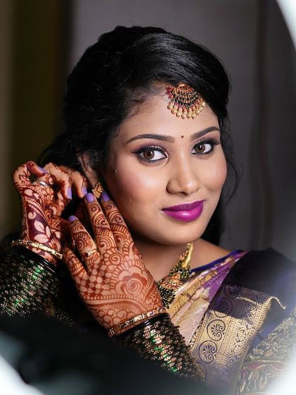 A classic "getting ready" shot of Aarthi. This close-up in the mirror highlights her striking eye makeup and bold lip color.
