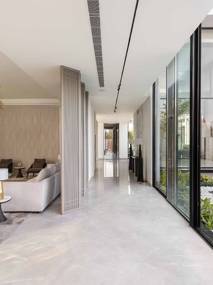 Here, the open corridor emphasizes the home's deep value for indoor-outdoor connectivity. The living and dining spaces flow seamlessly into one another and out towards the water feature and garden, creating a light and airy atmosphere.