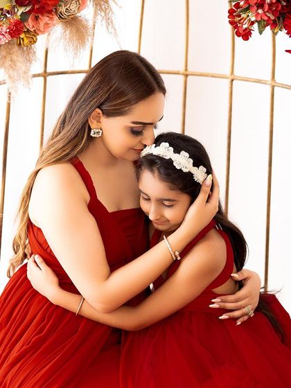 A tender hug between a mother and her daughter, both in beautiful matching red dresses. This is a perfect example of a heartfelt "mommy and me" portrait.