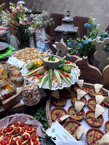 Our setups incorporate rustic and natural elements. This baby shower spread features wooden decor, fresh flowers, and an array of appetizers like bruschetta and chaat served in earthen bowls.